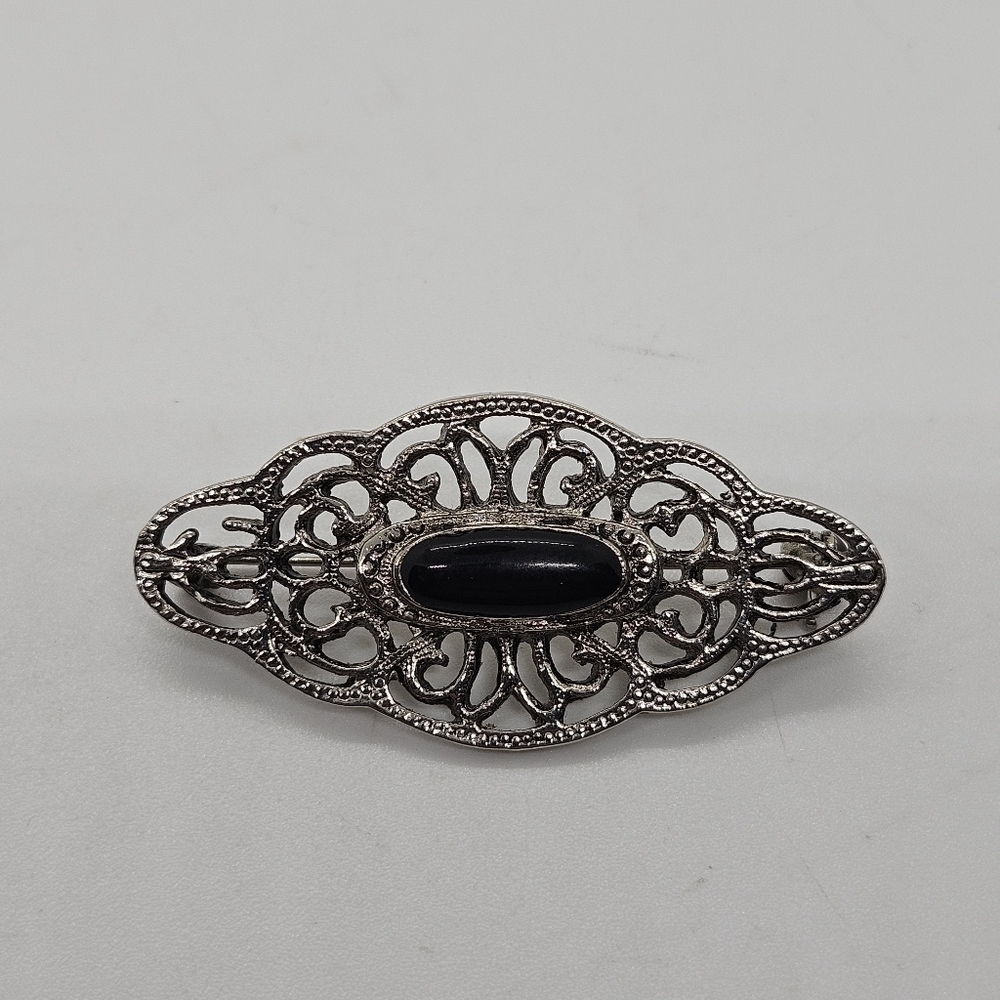 silver tone swirly brooch with black oval cabochon